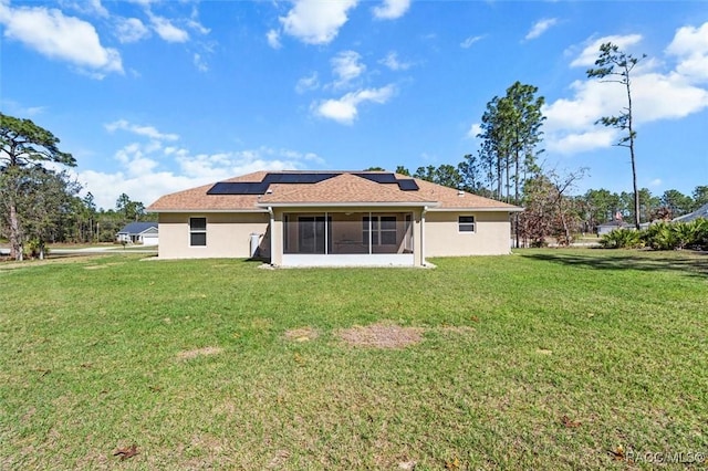 back of house with a yard, a sunroom, and solar panels