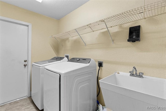 laundry area featuring independent washer and dryer, sink, a textured ceiling, and light wood-type flooring