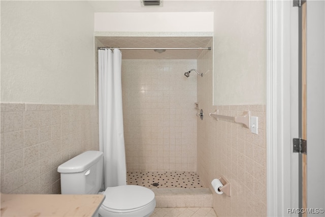 bathroom with curtained shower, tile walls, and toilet