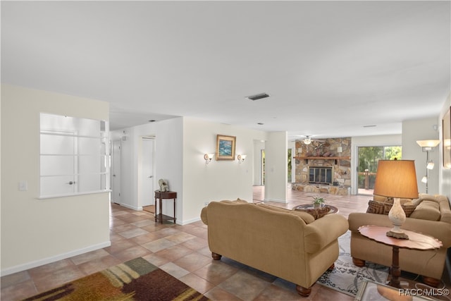 tiled living room with a stone fireplace and ceiling fan