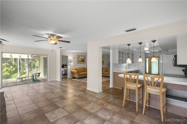 kitchen with sink, hanging light fixtures, ceiling fan, a kitchen bar, and kitchen peninsula