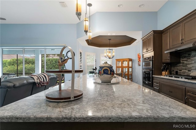 kitchen featuring a large island, decorative light fixtures, backsplash, and appliances with stainless steel finishes