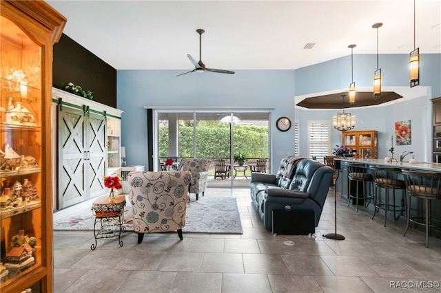 tiled living room featuring a barn door, sink, and ceiling fan with notable chandelier