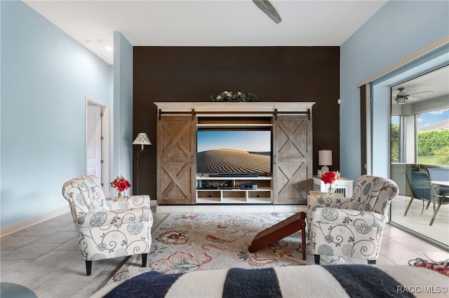 tiled living room featuring a barn door and ceiling fan