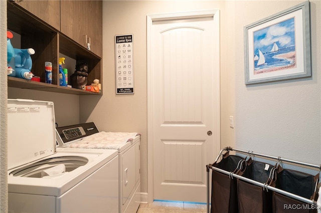 laundry room featuring cabinets, light tile patterned floors, and washing machine and clothes dryer