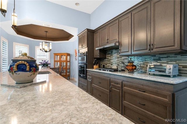 kitchen with appliances with stainless steel finishes, dark brown cabinetry, and a notable chandelier