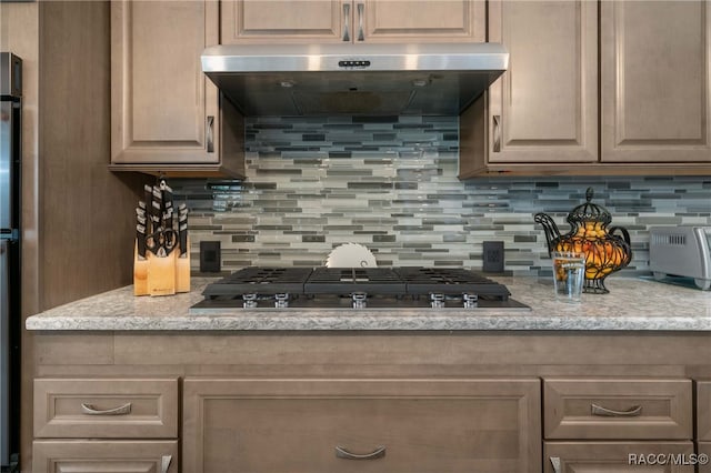 kitchen featuring light brown cabinets, backsplash, black gas cooktop, light stone counters, and extractor fan