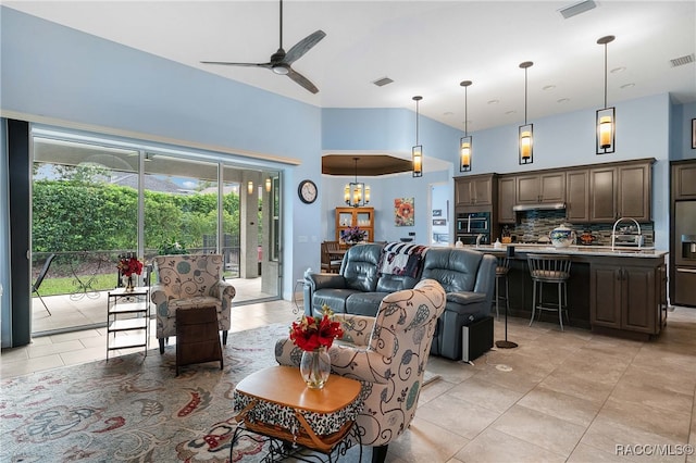 tiled living room with ceiling fan with notable chandelier, sink, and a high ceiling