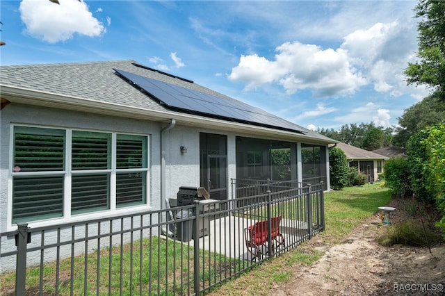 back of property featuring solar panels, a yard, and a sunroom