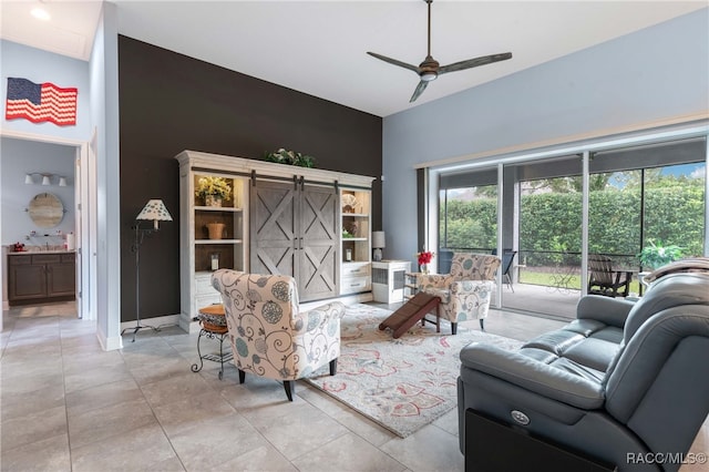 living room featuring a barn door, ceiling fan, and light tile patterned flooring