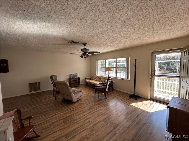 unfurnished living room featuring ceiling fan, dark wood-type flooring, and a textured ceiling