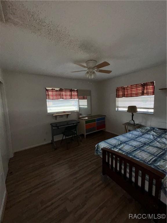 bedroom with ceiling fan, dark wood-type flooring, and a textured ceiling