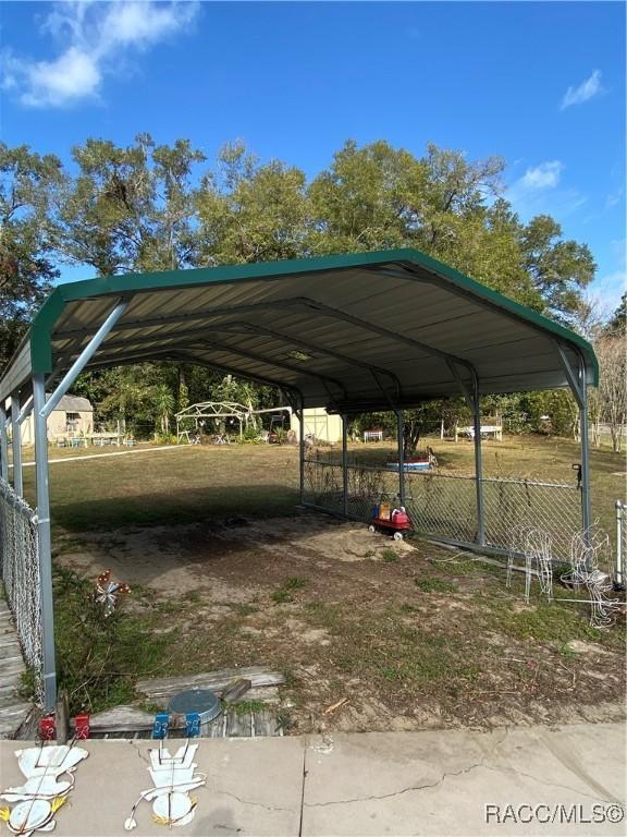 view of parking / parking lot with a carport and a lawn