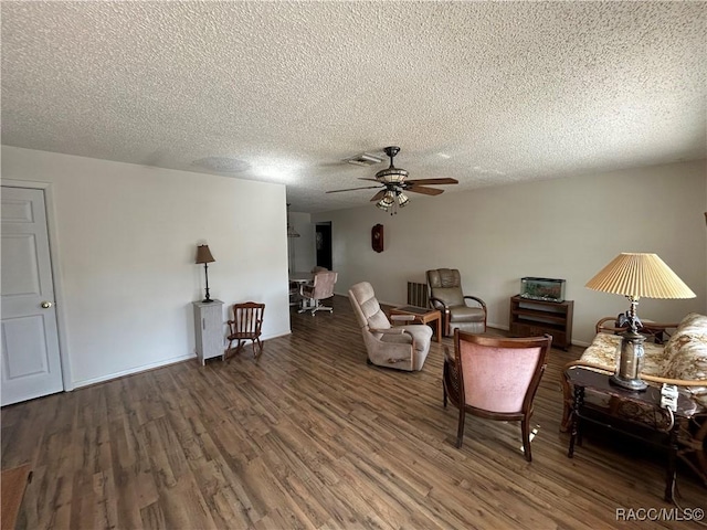 living room with a textured ceiling, dark hardwood / wood-style flooring, and ceiling fan