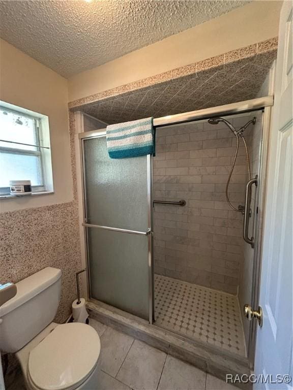 bathroom with tile patterned floors, a textured ceiling, an enclosed shower, and toilet