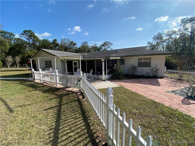 view of front facade featuring a front lawn, a patio area, and a sunroom