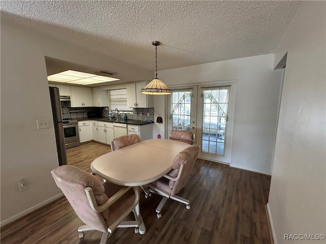 dining room with french doors, dark hardwood / wood-style flooring, a textured ceiling, and sink