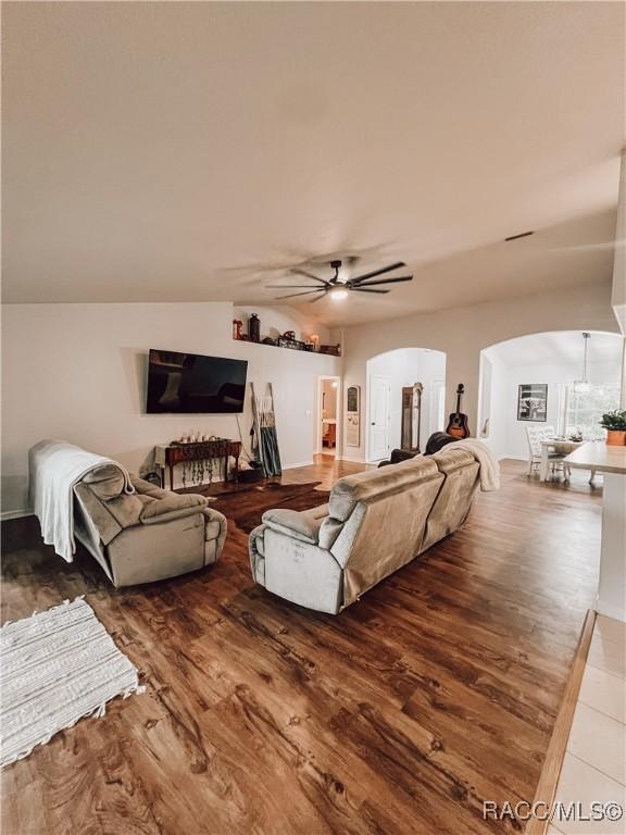 living room with arched walkways, ceiling fan, and wood finished floors