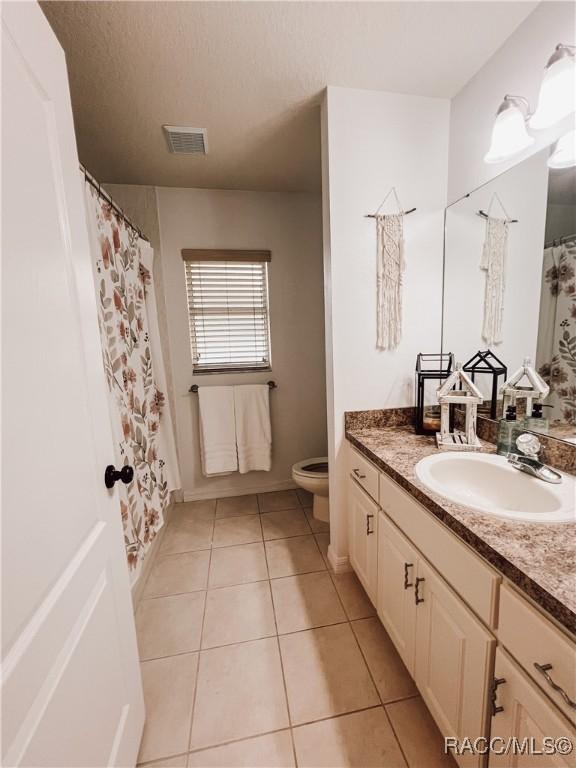 bathroom with visible vents, tile patterned floors, baseboards, vanity, and toilet