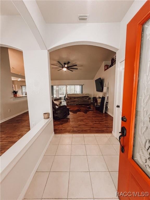 foyer with visible vents, lofted ceiling, arched walkways, a ceiling fan, and light wood-style flooring