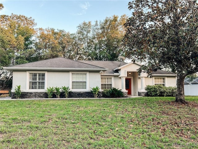 ranch-style home featuring stucco siding, a front yard, and stone siding