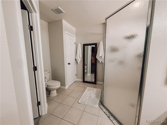 full bath featuring a textured ceiling, visible vents, tile patterned flooring, a shower stall, and toilet