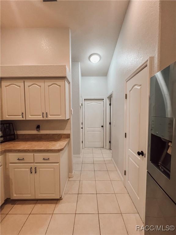 kitchen featuring light countertops, baseboards, light tile patterned floors, and stainless steel fridge with ice dispenser
