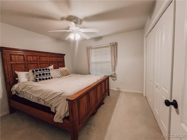 bedroom with baseboards, ceiling fan, a closet, and light colored carpet