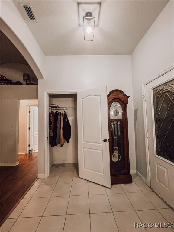 hall with baseboards, visible vents, and light tile patterned floors