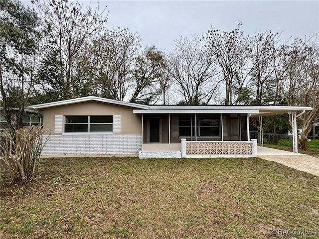 view of front of house with a carport, a front yard, concrete driveway, and brick siding