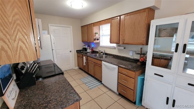 kitchen with dark stone counters, white appliances, sink, white cabinets, and light tile patterned flooring