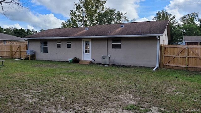 rear view of property featuring a yard and central AC