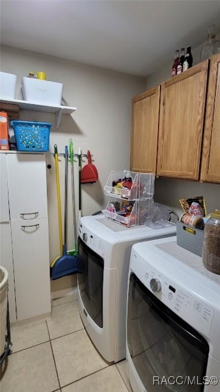 laundry area featuring separate washer and dryer, light tile patterned floors, and cabinets