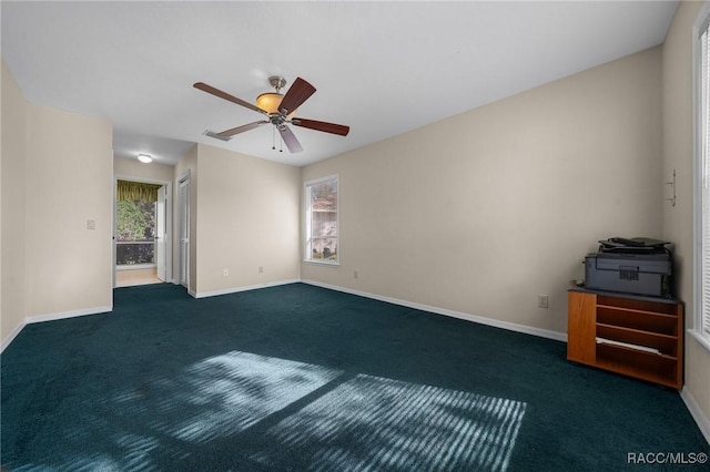 unfurnished room with dark carpet, a wealth of natural light, and baseboards