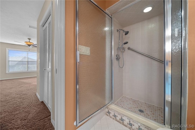 full bathroom featuring ceiling fan, a shower stall, and baseboards