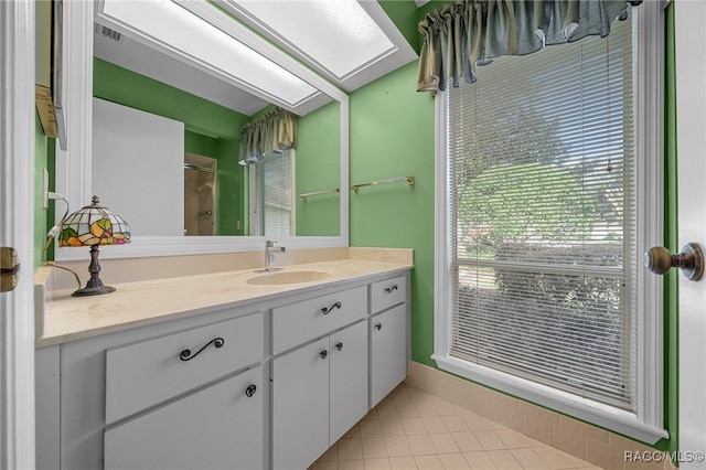 bathroom with a skylight, vanity, a shower, and tile patterned floors