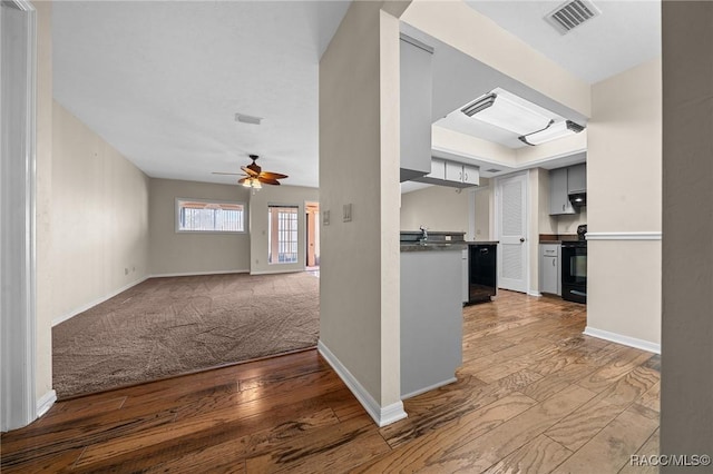 kitchen featuring hardwood / wood-style floors, electric range, visible vents, and a ceiling fan