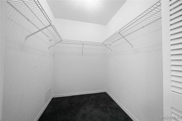 spacious closet featuring visible vents and dark carpet