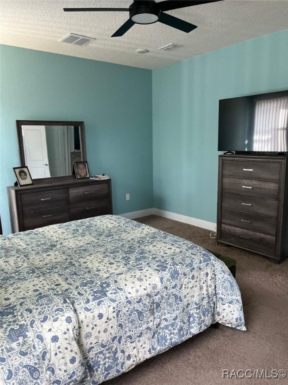 bedroom featuring ceiling fan, a textured ceiling, and dark carpet