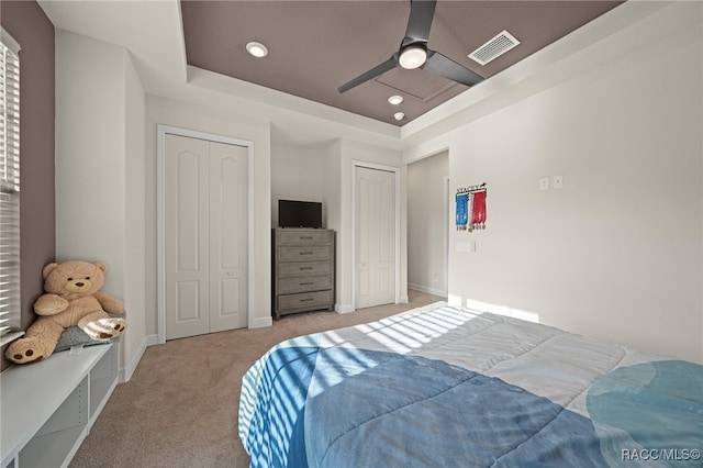 bedroom with light carpet, a tray ceiling, and ceiling fan