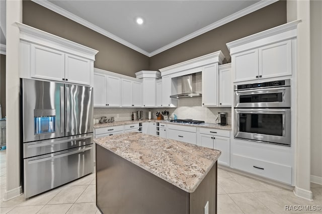 kitchen with light stone counters, white cabinets, stainless steel appliances, and wall chimney range hood