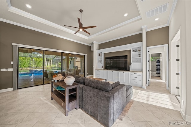 tiled living room with a raised ceiling, ceiling fan, and ornamental molding