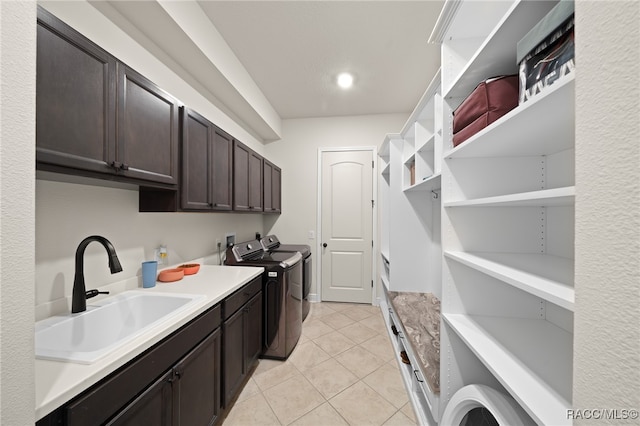 laundry room with light tile patterned flooring, cabinets, independent washer and dryer, and sink