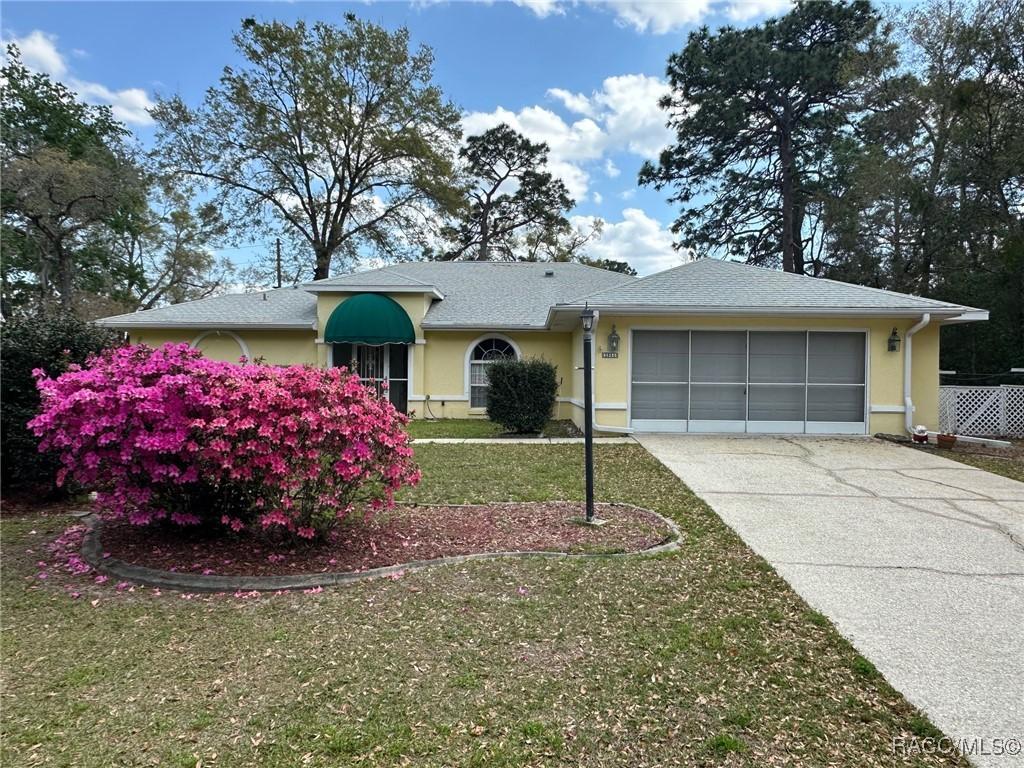 ranch-style house featuring a garage, stucco siding, driveway, and a front yard
