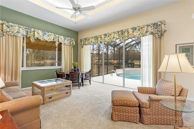 sitting room featuring a raised ceiling, ceiling fan, and carpet