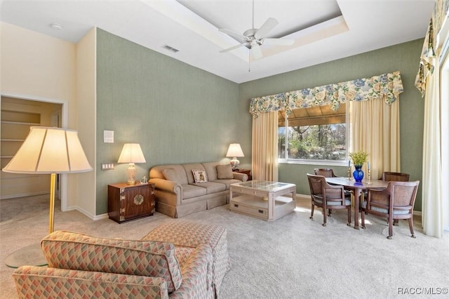 living room featuring a raised ceiling, ceiling fan, and carpet flooring