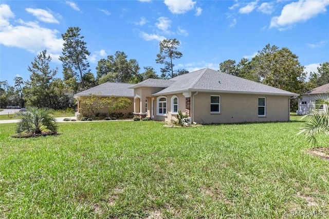 ranch-style home featuring a front lawn and stucco siding