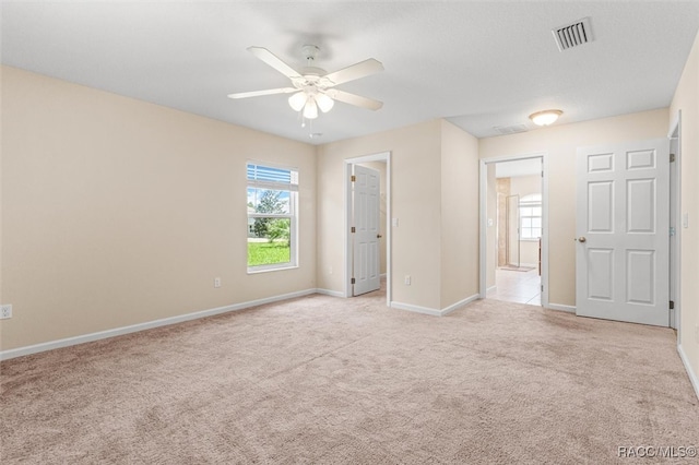 unfurnished bedroom featuring light colored carpet, visible vents, baseboards, and multiple windows