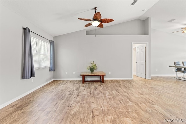 empty room with ceiling fan, vaulted ceiling, light wood-type flooring, and baseboards