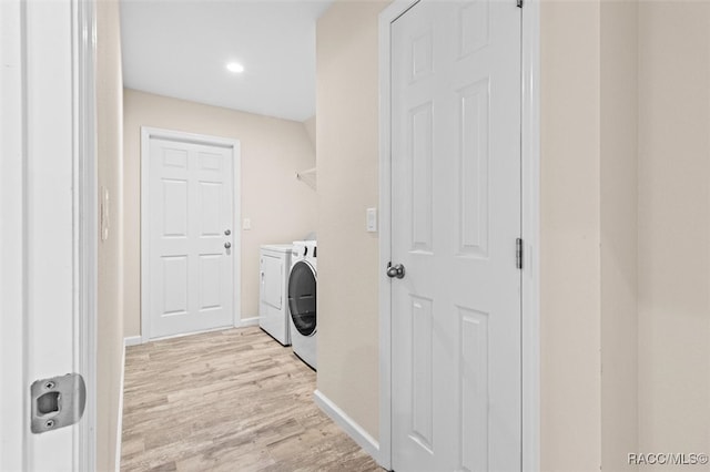 laundry area with laundry area, separate washer and dryer, light wood-style flooring, and baseboards